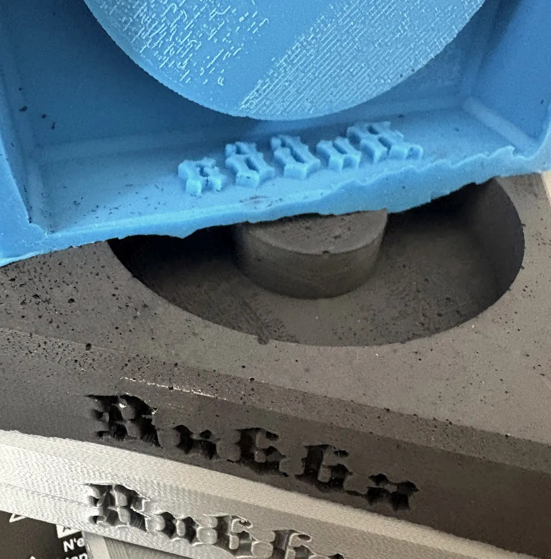 The mould lettering above the cast lettering it produces.