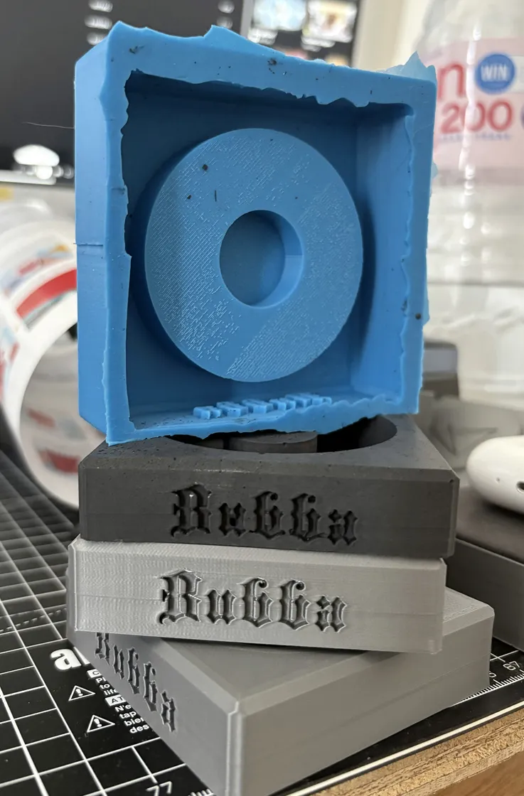 Silicone mould held above three cast and printed bases.