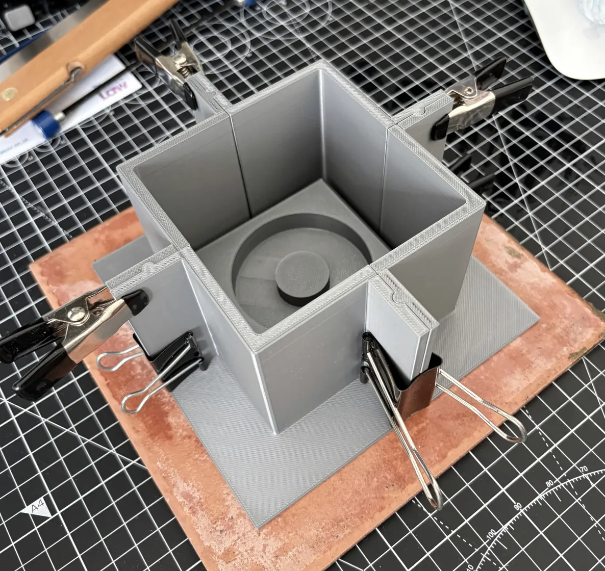 Printed mould box clamped shut on a tile, ready to pour.